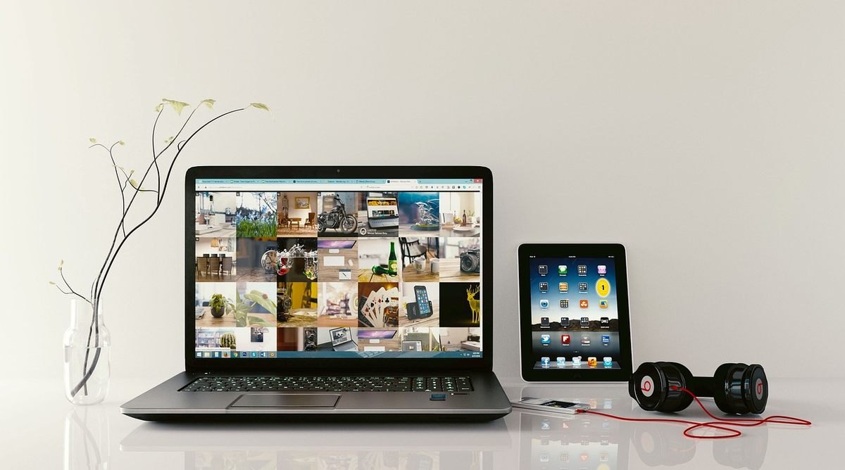 Laptop et tablette sur une table avec écouteurs et écran coloré