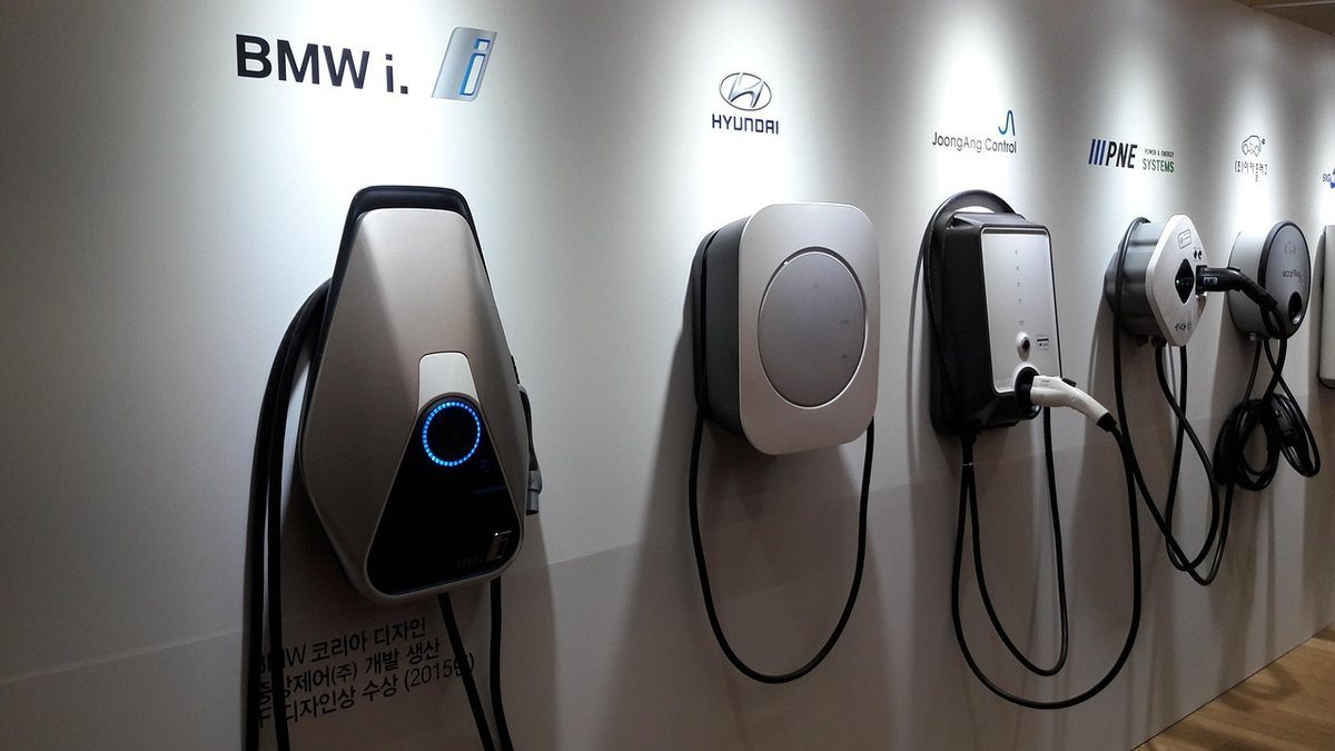 Quatre bornes de recharge pour véhicules électriques installées sur un mur blanc