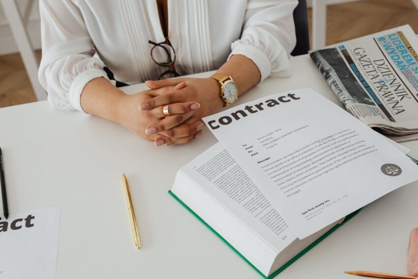 Une personne examine un contrat à un bureau avec des documents et un livre
