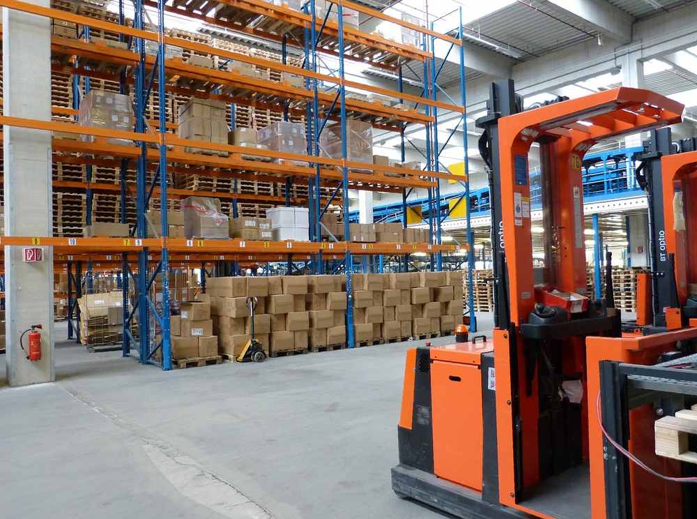 Un entrepôt avec des étagères hautes, des palettes et un chariot élévateur orange Un entrepôt avec des étagères hautes, des palettes et un chariot élévateur orange