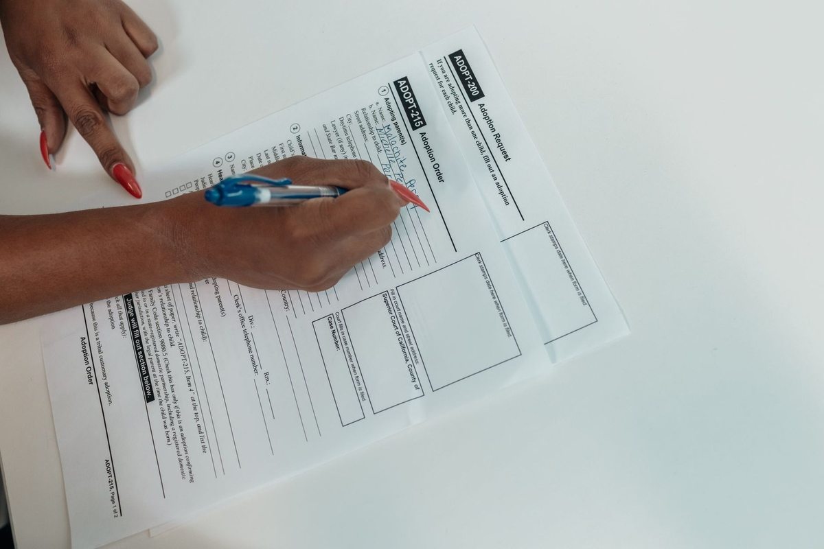Main gauche pointant vers document, main droite écrivant dessus avec stylo bleu Main gauche pointant vers document, main droite écrivant dessus avec stylo bleu