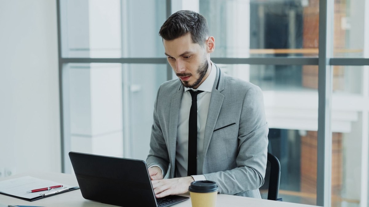 Un cadre professionnel travaille sur son ordinateur dans un bureau lumineux Un cadre professionnel travaille sur son ordinateur dans un bureau lumineux