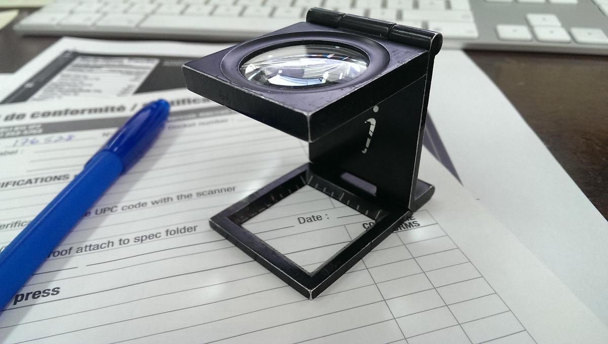 Une loupe sur un formulaire avec un stylo bleu